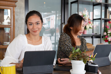 Portrait of businesswoman working with tablet while sitting next to coworker in office room