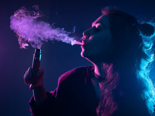 Vape smoke comes out of woman mouth. Portrait of a vaper on a dark background. Young girl blows out steam from a vape. Vaping pen in student hand. Vape smoke next to girl lips.