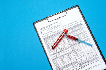 Clipboard with paper blank form with blood test tubes on blue background