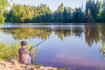 A teenage European boy fishing with a fishing rod in the summer. Fishing on the river in Russia.