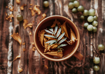 herbal tea. herbal tea in an orange mug on a wooden table. berries, herbs, flowers and tea on a brown wooden table. summer still life with herbs on the kitchen table