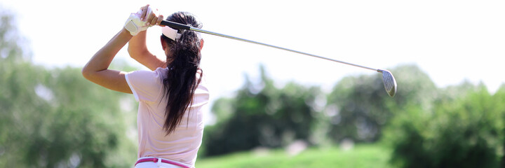 Female golfer stands with her back making swing with club. Golfing around the world concept