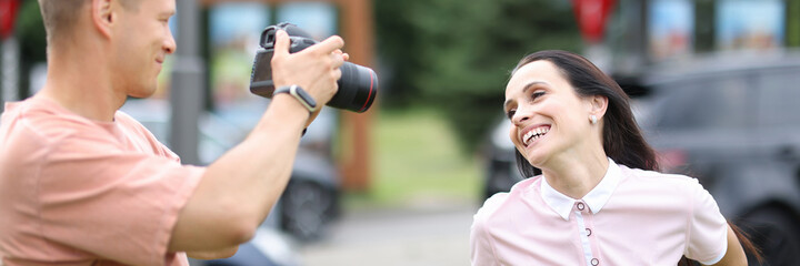 Male photographer with camera photographs smiling woman. Professional services photographer concept
