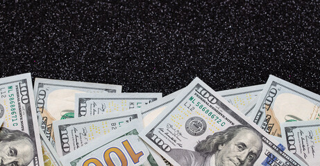 100 dollar banknotes on black glitter background