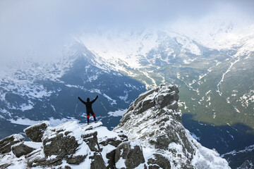 Landscape on the cold winter day . Happy tourist is standing at the edge of the precipice. High mountains with snow white peaks. Snowy background. Location place the Carpathian, Ukraine, Europe.