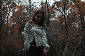 Naklejka na ściany i meble Girl in a white shirt in a dark forest
