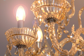 Chandelier of yellow crystal hanging with light energy saving bulbs.