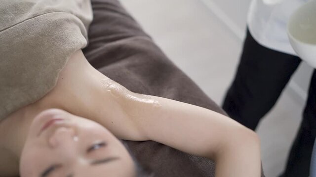 エステサロンで脇に脱毛用の冷却ジェルを塗る日本人女性