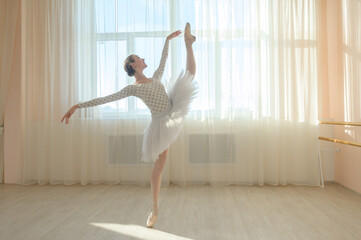 Beautiful ballerina in body and white tutu is training in a dance class. Young flexible dancer...