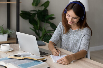 Happy smart millennial european appearance woman wearing headphones, involved in listening...