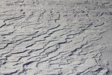 Snowy white background. The texture of the snow. Shiny snow with bokeh and blurred background close-up. White snow-covered field. Macro photo of snow.