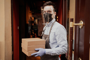Accepts courier delivery of products to the restaurant cafe. a male waiter stands in a protective...