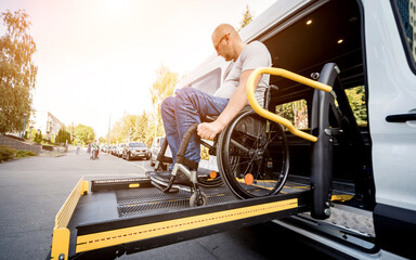 A man in a wheelchair on a lift of a vehicle for people with disabilities