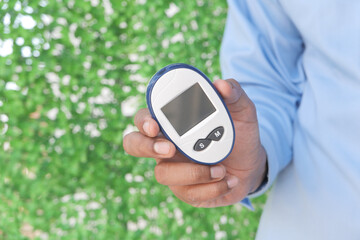 young man holding diabetic measurement tool outdoor with copy space 