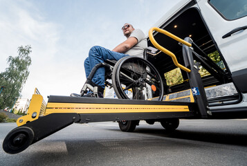 A man in a wheelchair on a lift of a vehicle for people with disabilities