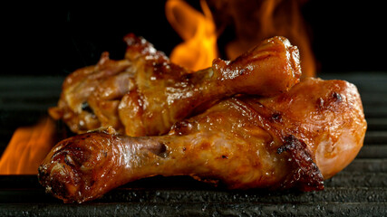 Tasty Chicken Legs on Cast Iron Grate with Fire Flames. Freeze Motion Barbecue Concept.