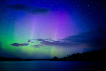 Northern lights dancing over calm lake in Farnebofjarden national park in north of Sweden.