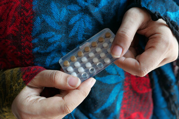 women hand holding birth control pills close up 