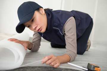 Obraz premium woman fitting roll of underlay to the floor