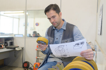 man holding trolley wheel and fitting instructions