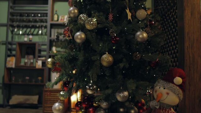 A beautiful Christmas tree beautifully decorated with gold, silver and red ornaments, snowflakes, deer and pine cones keeps the winter night of December warm. Merry Christmas!
