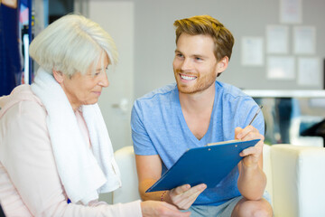Obraz premium fitness center worker filling out paperwork with senior woman