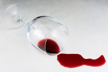 An overturned glass with wine spilled on the table.