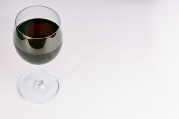 Glass with red wine on a white table. Copy space.