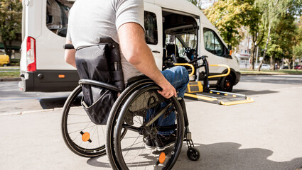 A man in a wheelchair moves to the lift of a specialized vehicle 
