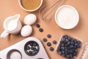 Ingredients for Baking Muffins or Cup Cakes Baking Dish Milk Eggs Sugar Flour Light Brown Background Top View Horizontal Copy Space