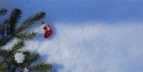 Decorative composition with a branch of a Christmas tree on the sunny snow for a New Year background or greeting card.