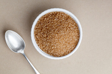 Brown refined sugar in a bowl on a beige background. Cane sugar