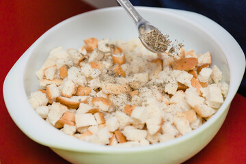 dried bread cubes being seasoned to become a dressing casserole for a holiday dinner