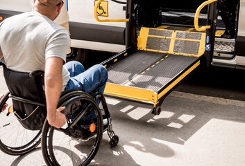 A man in a wheelchair moves to the lift of a specialized vehicle 