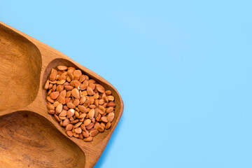 Roasted almonds in an eco-friendly wooden container on a blue background