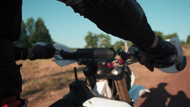 Close up tracking shot of unrecognizable man in full riding gear sitting on motorcycle and revving engine outdoors