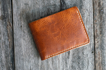 Tan brown leather bifold wallet on wood background