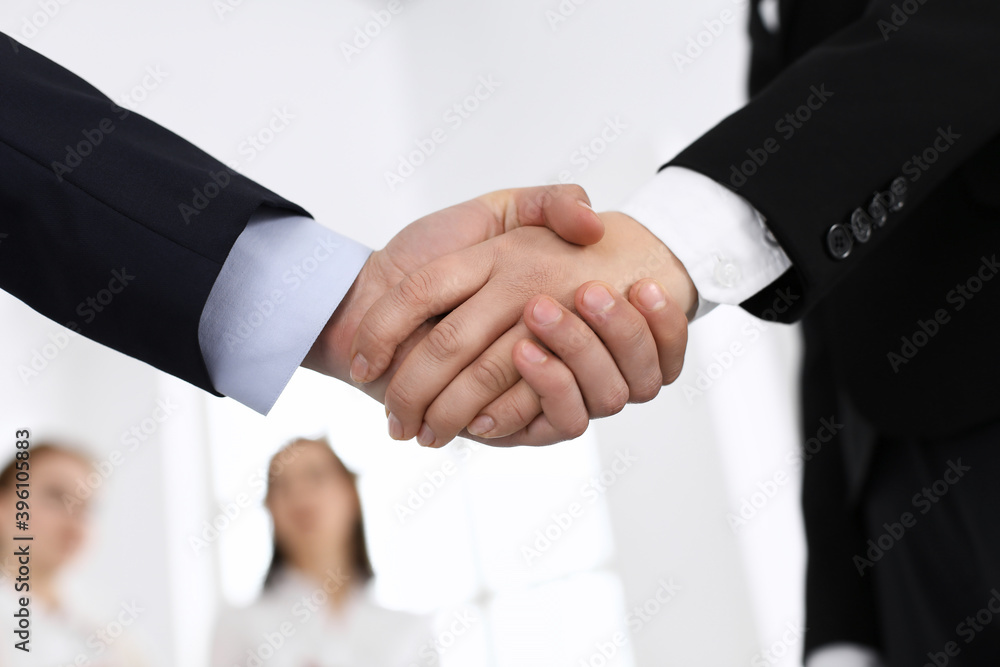 Wall mural businessman and woman shaking hands in office. concept of handshake as success symbol in business