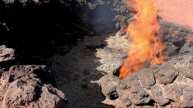 Fire flames coming out of volcanic crater in Timanfaya National park, Canary Islands. Hay burning due to ground heat in Lanzarote, Spain. Geothermal energy demonstration