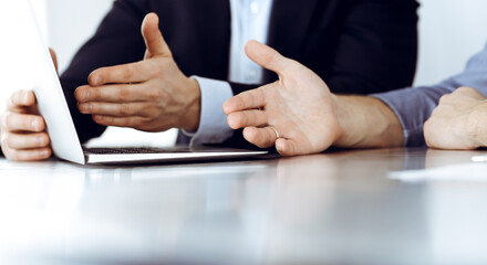 Obraz premium Business people using laptop computer while working together at the desk in modern office. Unknown businessman or male entrepreneur with colleague at workplace. Teamwork and partnership concept