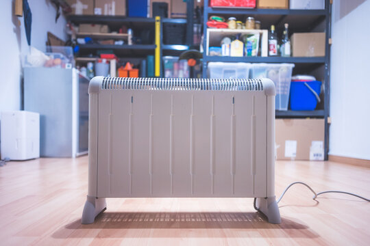 Heating The Basement With Electric Heater. Blurry Boxes And Shelfs In The Background