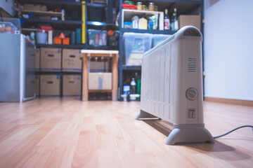 Heating the basement with electric heater. Blurry boxes and shelfs in the background
