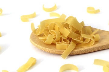 On a wooden spoon are pasta in the form of short noodles
