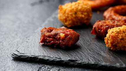 Fried Buffalo onion rings, tater tots and sweetcorn fritters with ketchup on rustic stone board. Party take away food