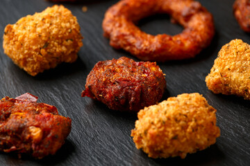 Fried Buffalo onion rings, tater tots and sweetcorn fritters with ketchup on rustic stone board. Party take away food