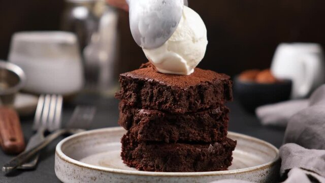 Chocolate brownies with scoop of vanilla ice cream. Putting ice cream on stack of brownies