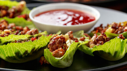 Chilli Beef Lettuce Wraps with sauce on black plate