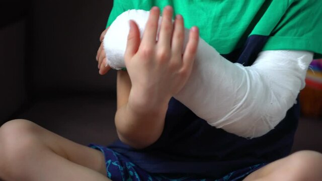 little boy lies on the bed with a fractured limb. a child's arm is broken. fracture injury. plaster cast on the arm