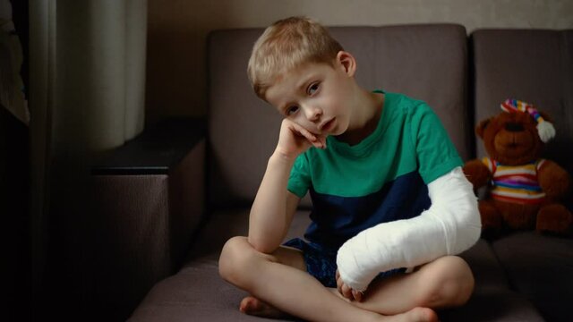 little boy lies on the bed with a fractured limb. a child's arm is broken. fracture injury. plaster cast on the arm