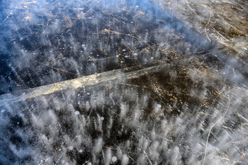 Textured surface of lake, river or puddle at winter. Frozen air bubbles in the ice. Frozen river. man stands on the ice